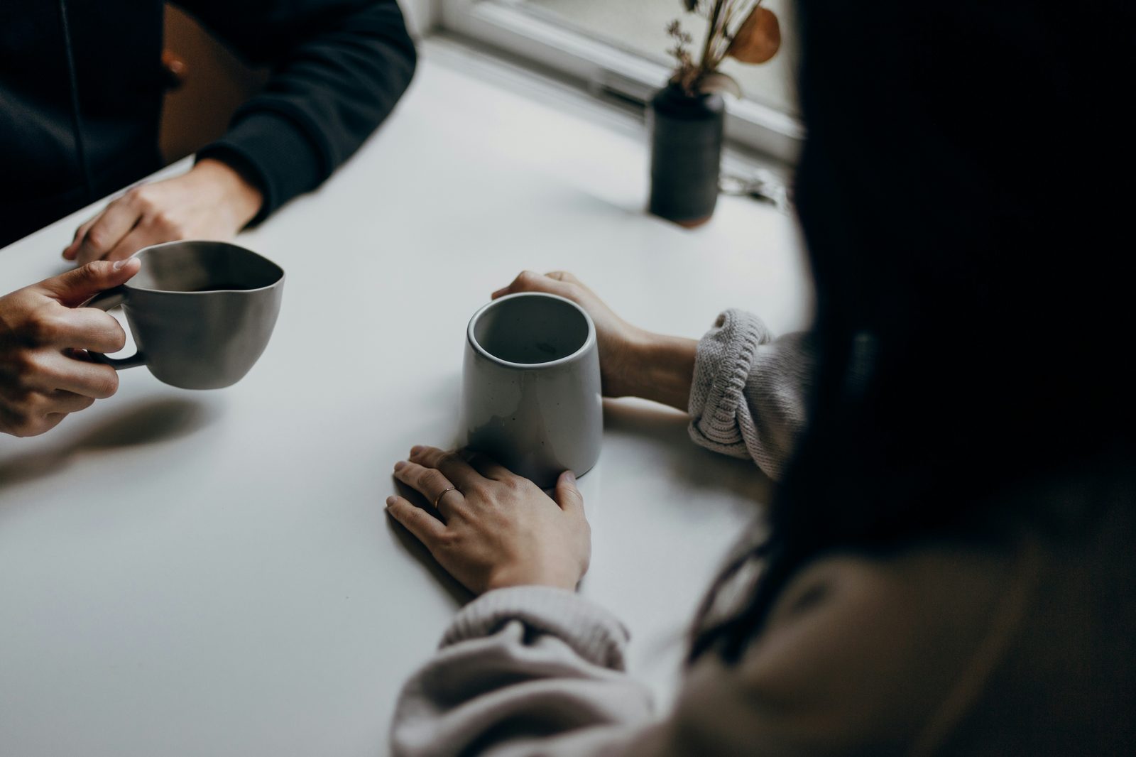 Two people holding coffee mugs, mid-conversation